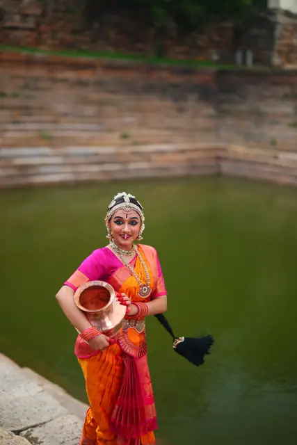 Carrying a ceremonial pot by the temple pond