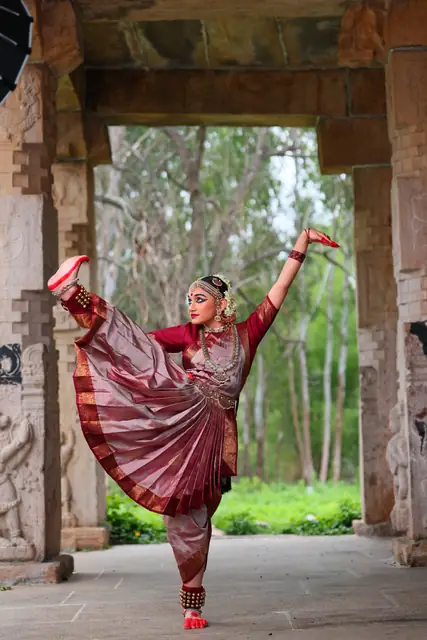 In maroon costume framed by a temple arch