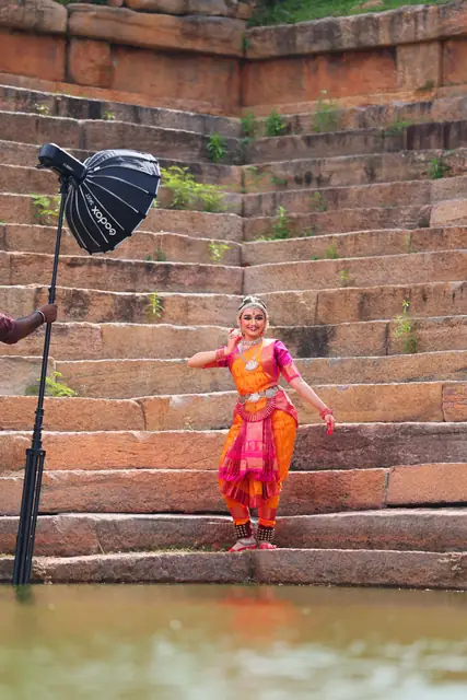 On weathered stone steps with a palm-leaf umbrella