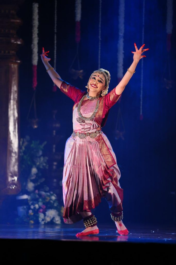 Ananya standing with arms raised in a joyful Bharatanatyam pose